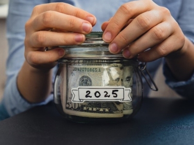 Female hands holding glass jar full of American currency dollars cash banknote with text 2025 year