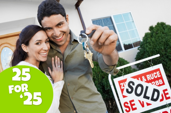 couple stand by SOLD sign holding keys to their new home