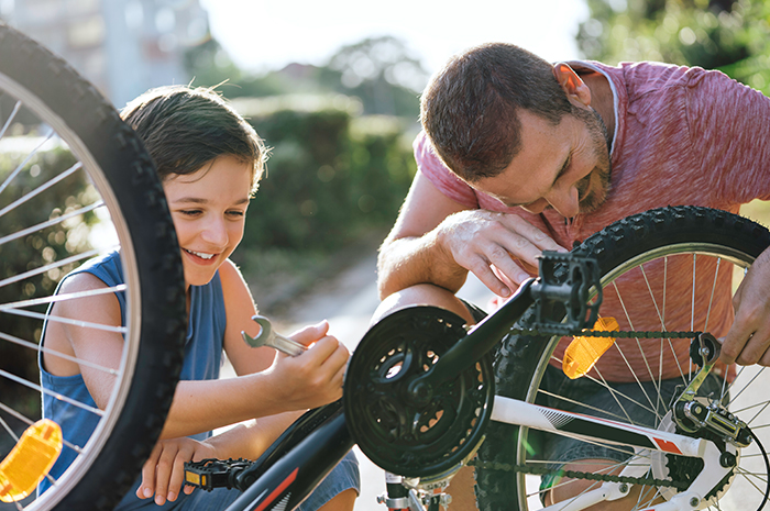 father helping son maintain a bicycle