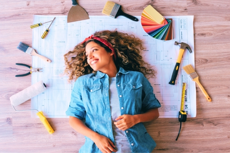woman laying on floor surrounded by home improvement tools and blueprints