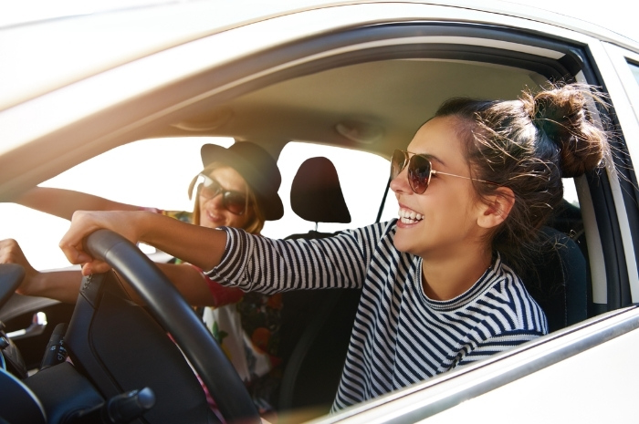 two happy females driving in a white car
