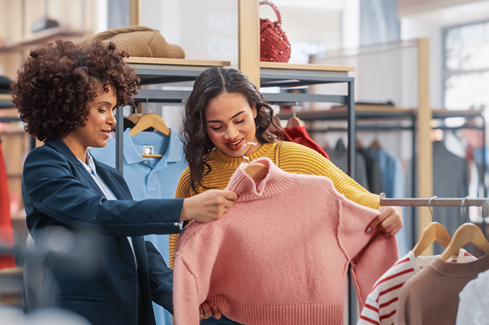 two people shopping, looking at a sweater