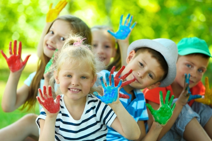 children hold up painted hands as they prepare to make hand art