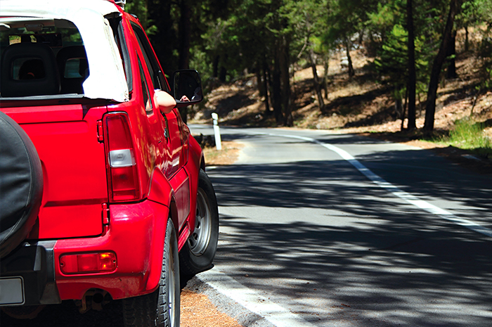 red vehicle beside a paved road