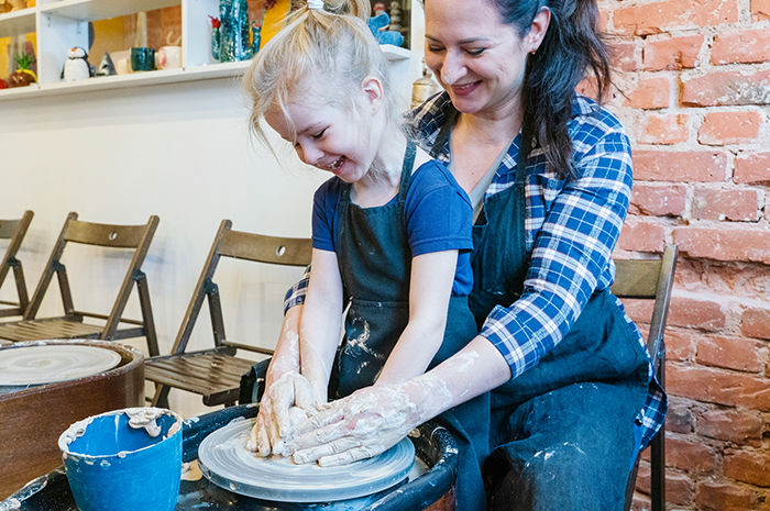 adult woman is teaching girl about pottery