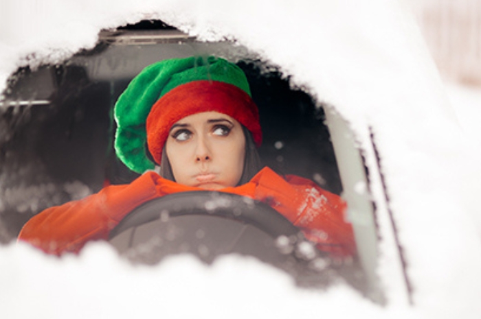 young woman looking out the window of a snow-bound car